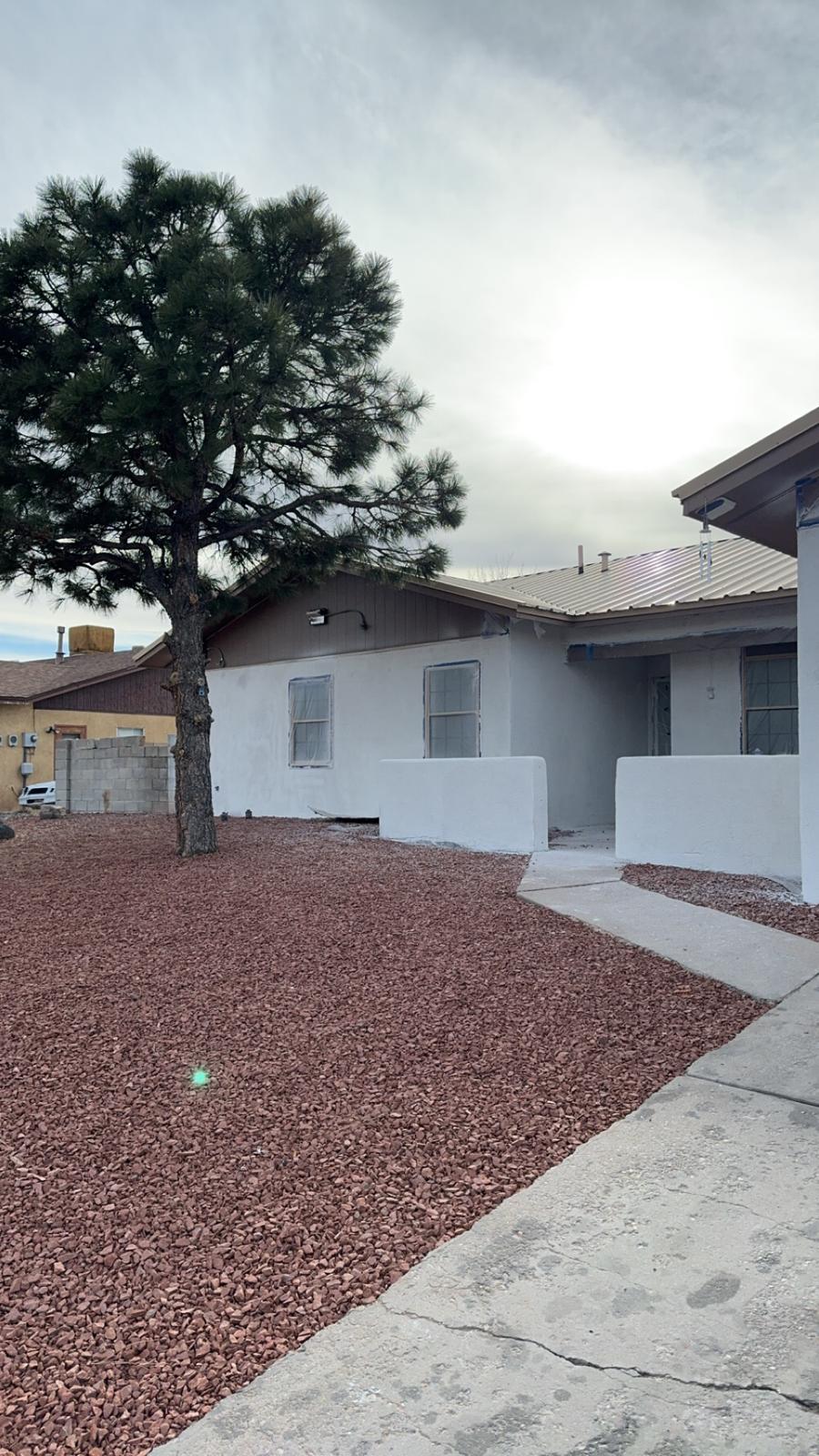 Home exterior mid-renovation with fresh stucco and gravel landscaping